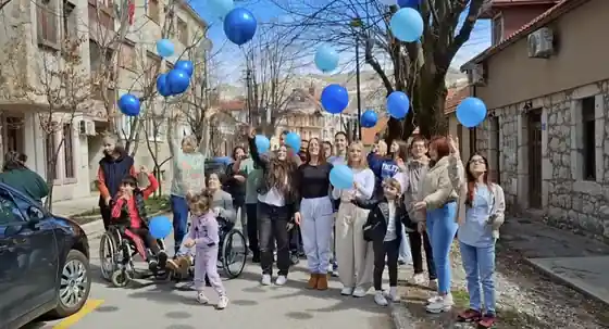 Razvitak members and participants holding blue balloons on a street in Cetinje